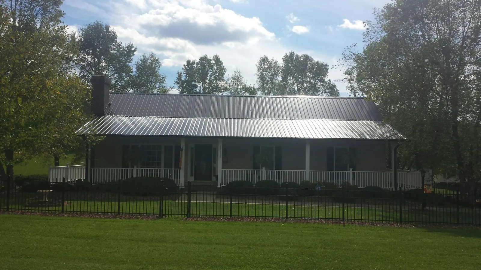 Gray metal roof on a brick ranch with a full width front porch — Gutter Guard Installation work by our crew in White Hall