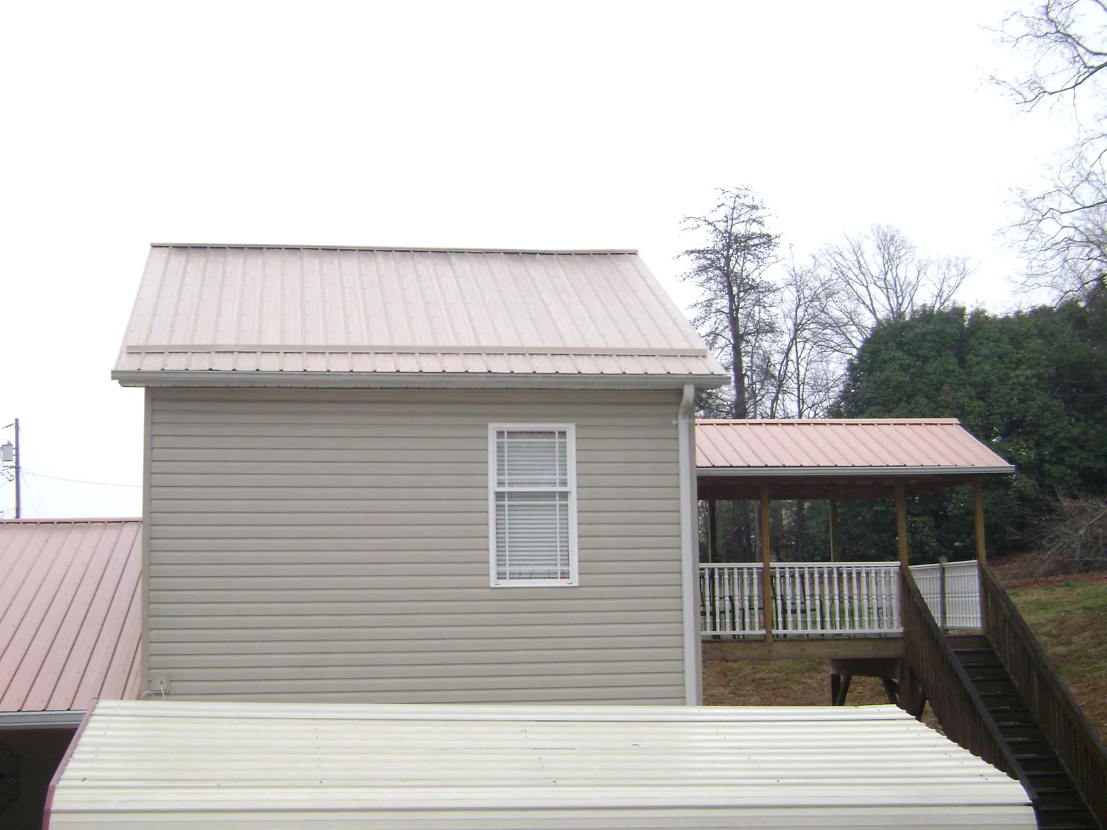 Tan metal roofs on a two story addition and attached porch, from a Roof Replacement job in White Hall