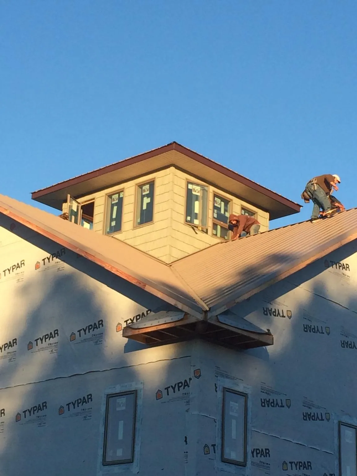 Roofers working around a rooftop cupola on a new metal roof at sunset — Roof Waterproofing in White Hall by Roofing Brothers